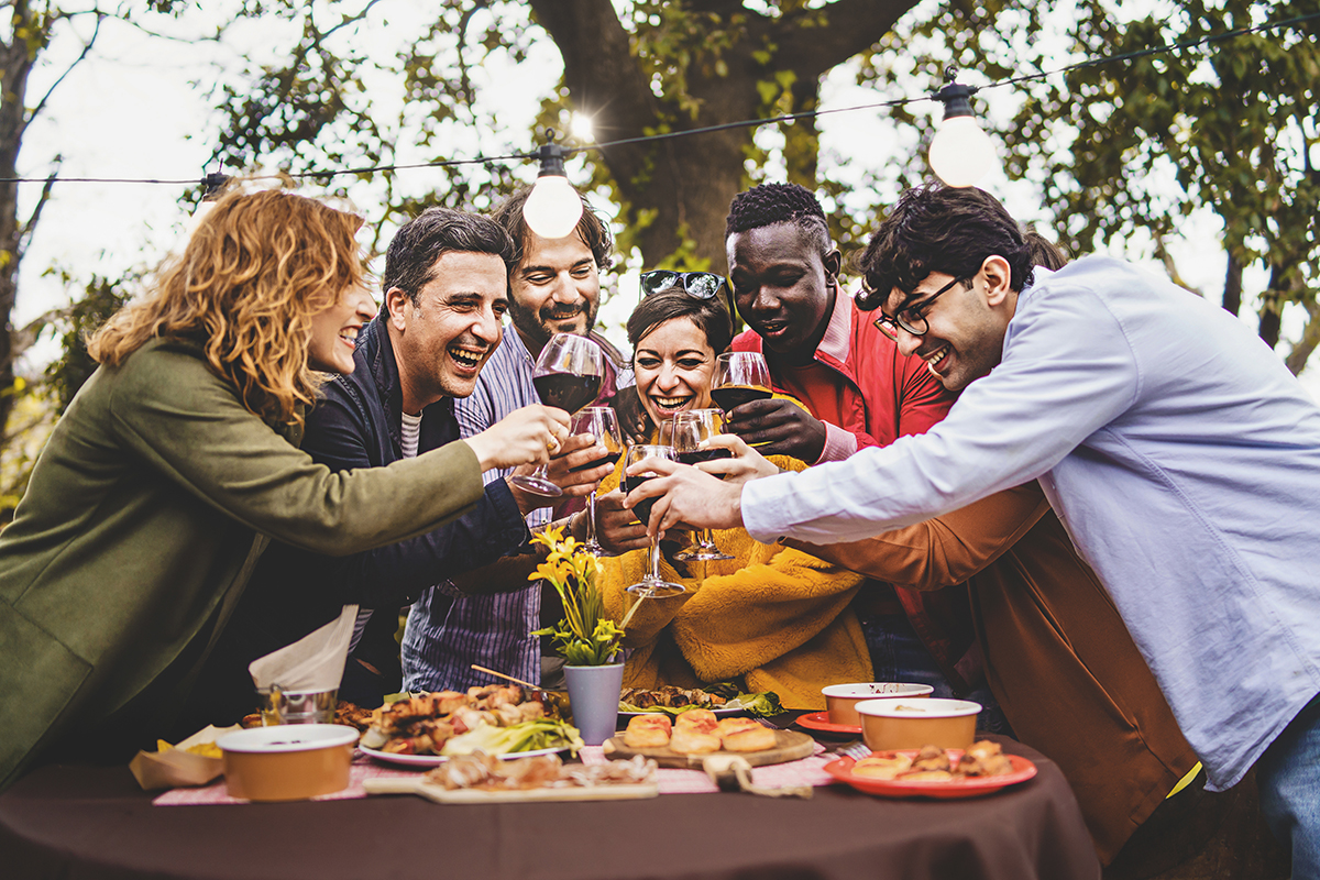 Company of cheerful friends having fun toasting pic nic in farmh