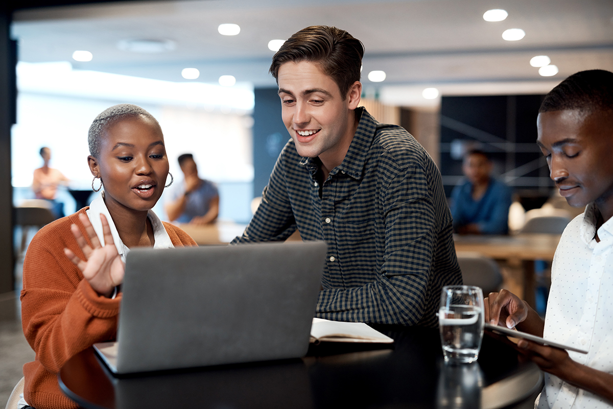 Shot of a group of young businesspeople using a laptop during a conference in a modern office.